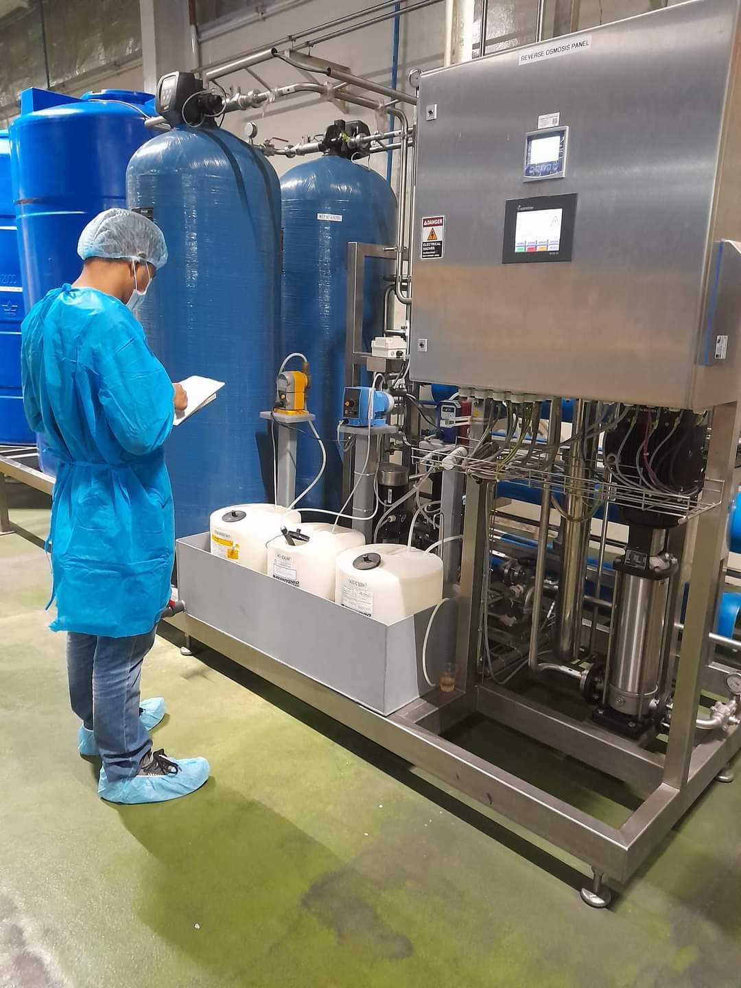 A technician in a hard hat providing on-site maintenance for industrial water pumps.